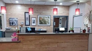 Una reception con finiture in legno, opere d'arte appese al muro e un tappeto di benvenuto all'ingresso.