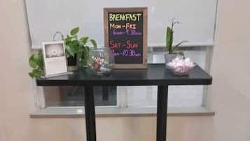 Una mesa de desayuno con un cartel de pizarra que indica los horarios del desayuno.