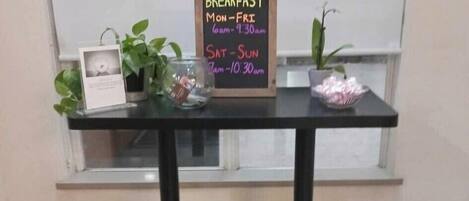 Una mesa de desayuno con un cartel de pizarra que indica los horarios del desayuno.