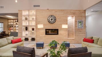 A modern living room with a large wall clock, built-in shelving, and a fireplace.
