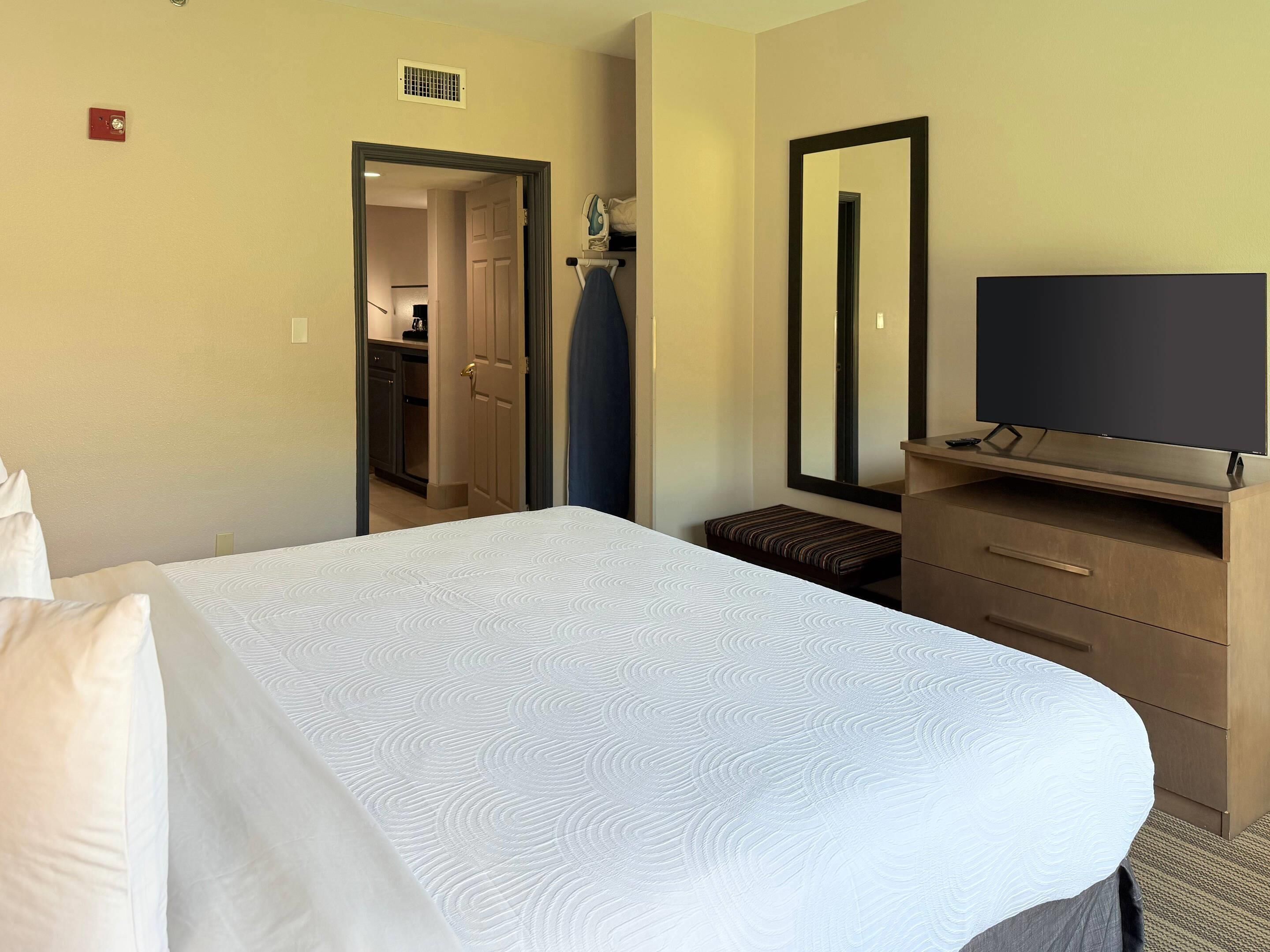 A hotel room with a bed, a TV, a dresser, and a mirror.