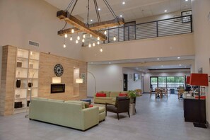 A spacious lobby with a high ceiling, a wooden beam structure, and a large clock on the wall.