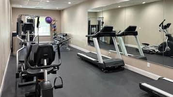 Une salle de sport équipée de tapis de course, de vélos elliptiques et de poids libres.