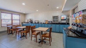 Eine moderne Küche mit blauen Schränken, einer Kaffeemaschine und einem Essbereich mit Holztischen und -stühlen.