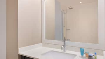 A bathroom with a white sink, a mirror, and a shower.