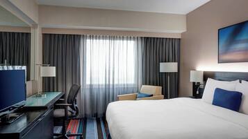 Une chambre d’hôtel avec un grand lit, un bureau avec un ordinateur, une chaise et un téléviseur.