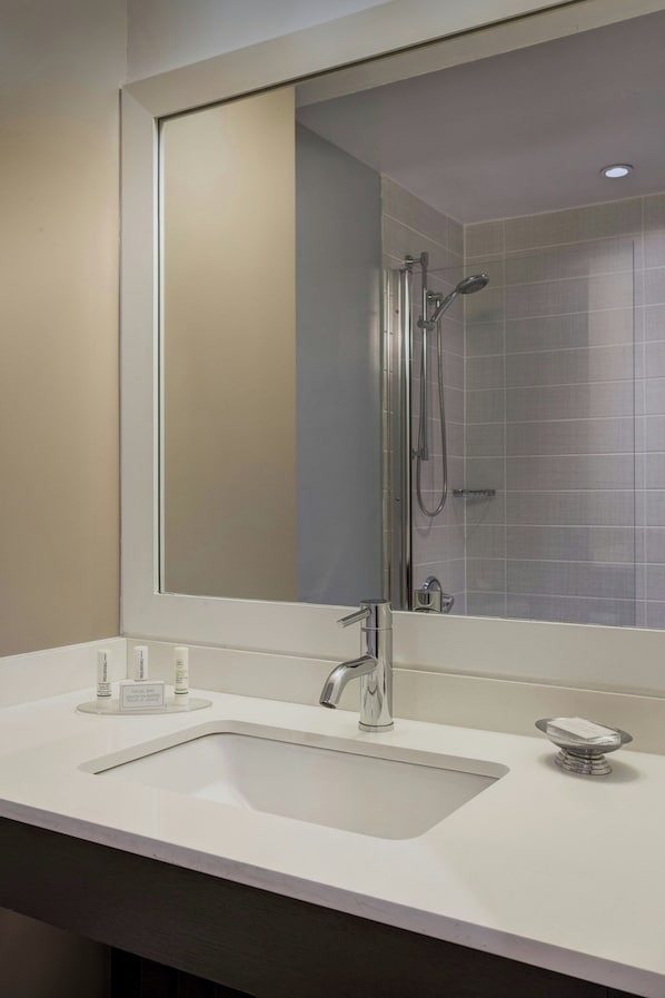 A modern bathroom with a large mirror, a sink, and a shower.