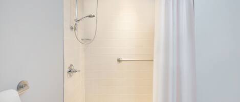A bathroom with a shower, toilet, and towel rack.