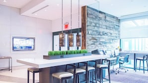 A modern bar area with a long counter, bar stools, and hanging pendant lights.