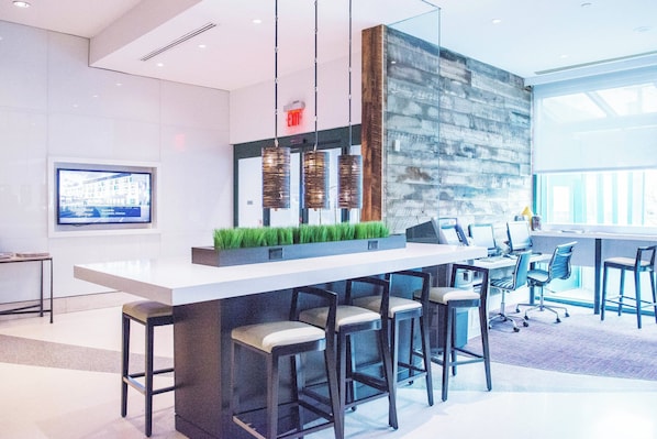 A modern bar area with a long counter, bar stools, and hanging pendant lights.