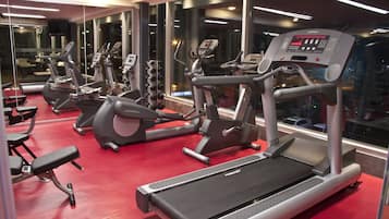 Une salle de sport équipée de tapis de course, de vélos elliptiques et d’appareils de musculation.