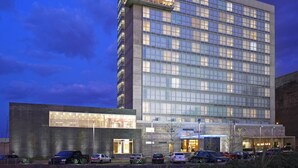 A multi-story hotel with a modern glass facade, a prominent sign reading "CASA INN," and several parked cars in front. - Casa Inn Premium Hotel Queretaro (El Marques)