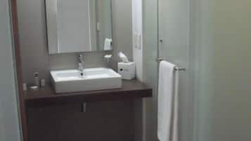 A small, modern bathroom with a white sink, mirror, and towel rack.