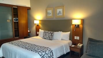 A hotel room with a large bed, two bedside lamps, a bedside telephone, and a wardrobe with a microwave.