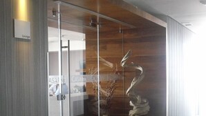 A modern office space with a glass partition, a wooden accent wall, and a decorative metal sculpture. - Casa Inn Premium Hotel Queretaro (El Marques)