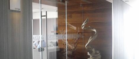 A modern office space with a glass partition, a wooden accent wall, and a decorative metal sculpture.