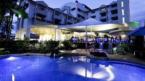 A modern hotel with a swimming pool, outdoor bar, and multiple balconies. - Cairns Sheridan Hotel (Cairns North)