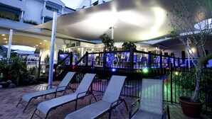 Un bar en la azotea con sillones y una sombrilla grande.