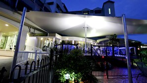 Un hotel moderno con un área exterior cubierta, una escalera y vistas de la calle por la noche.