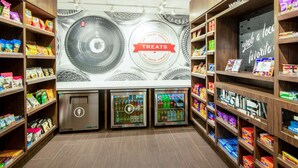 A snack display area with shelves stocked with various packaged snacks and a refrigerated section. - Hampton Inn & Suites Las Vegas-Henderson (Henderson)