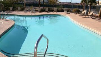 A swimming pool with lounge chairs and a tiled deck.