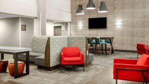 A modern hotel lobby with a seating area, a reception desk, and a flat-screen TV mounted on the wall. - Hampton Inn & Suites Las Vegas-Henderson (Henderson)