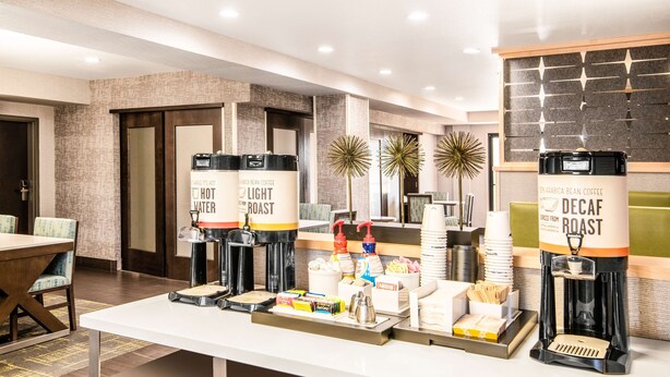 A coffee station with multiple coffee dispensers labeled "Hot Water," "Light Roast," and "Decaf Roast." - Hampton Inn & Suites Las Vegas-Henderson (Henderson)