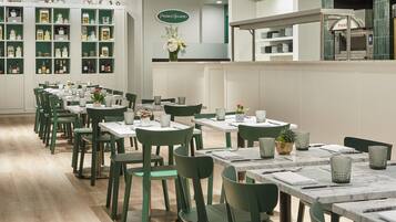 A restaurant with green chairs and tables, a display of kitchenware, and a sign for Pierrot Gourmet.