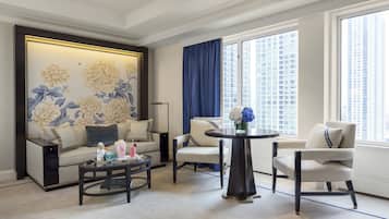 Un salon moderne comprenant un canapé, deux fauteuils, une table basse et un mur décoratif orné de motifs floraux.