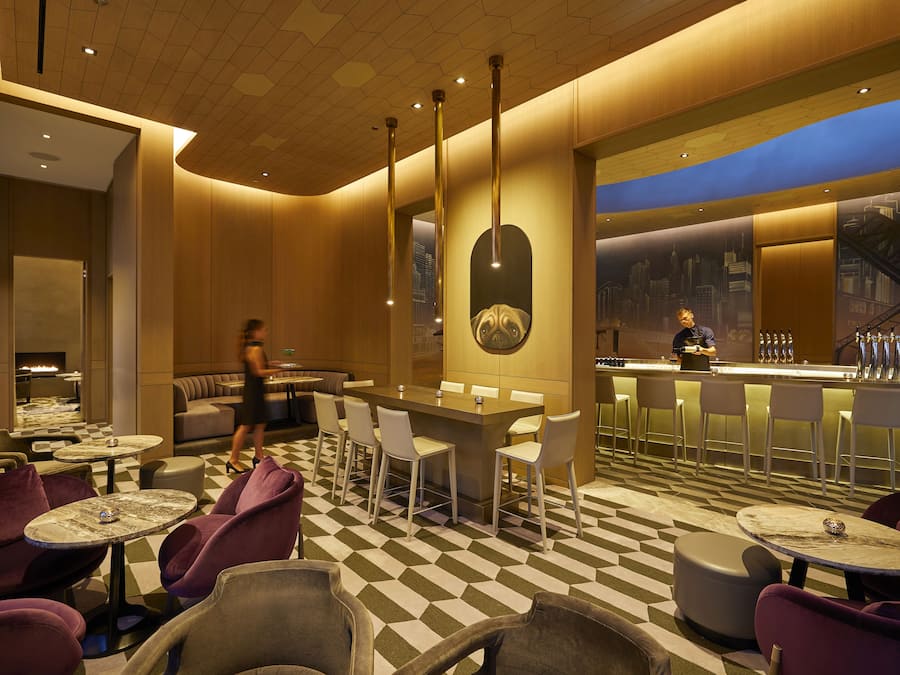 A modern bar area with a checkered floor, bar stools, and a bar counter.