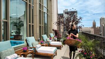 Un salon sur le toit avec des chaises longues, une piscine et une vue sur la ville.