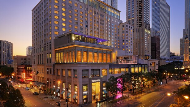 Un hotel de gran altura con varios pisos, grandes ventanales y una destacada tienda Tiffany & Co. en la planta baja.