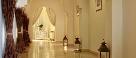 A corridor with a white console table, a vase of flowers, and three lit lanterns.