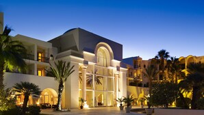 A hotel with a courtyard, palm trees, and a large arched entrance. - The Residence Tunis (La Marsa)