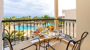 A balcony with a table set for breakfast overlooking a pool and beach. - The Residence Tunis (La Marsa)