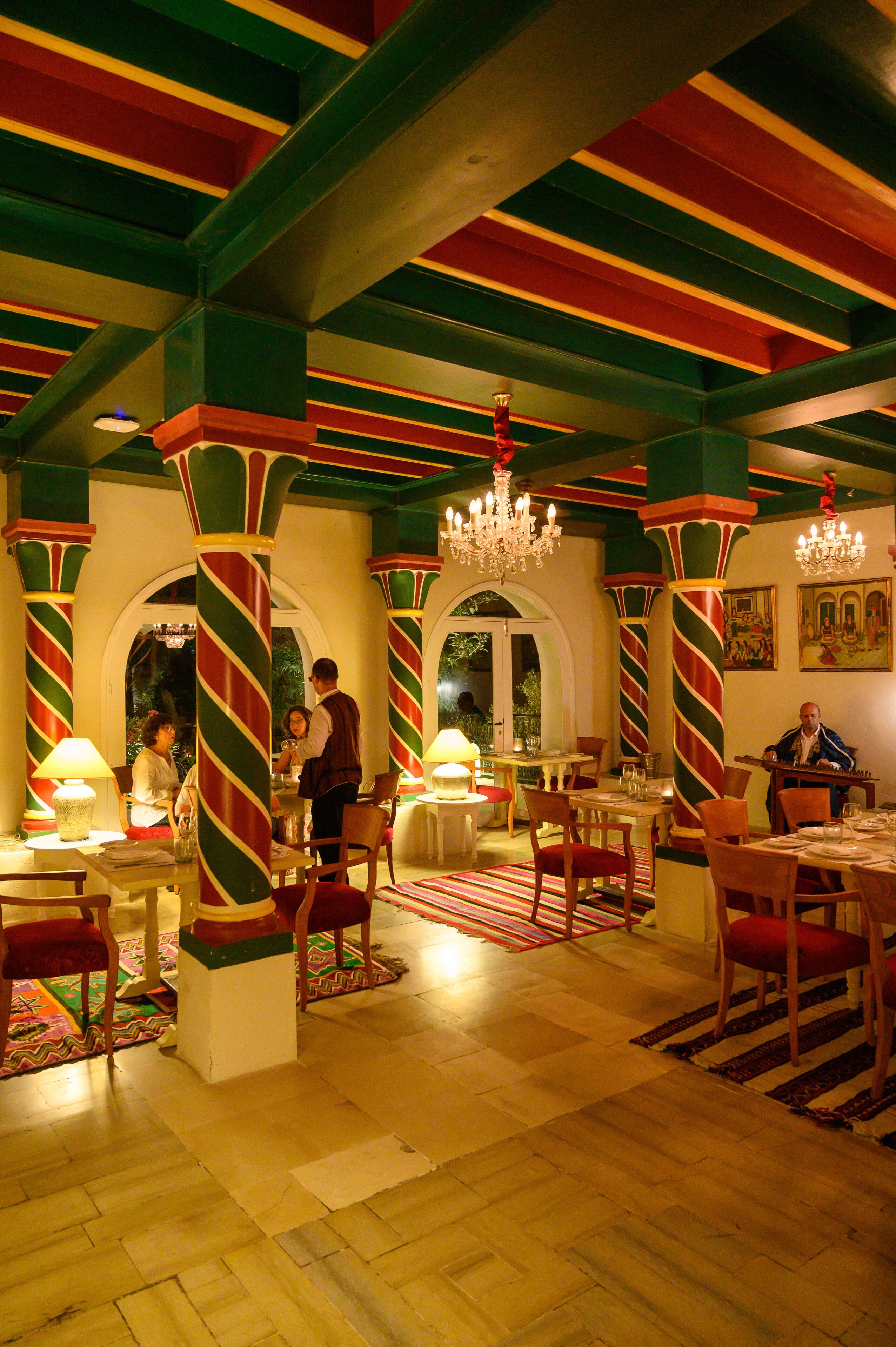 A restaurant with a colorful striped ceiling, wooden tables, and chairs.