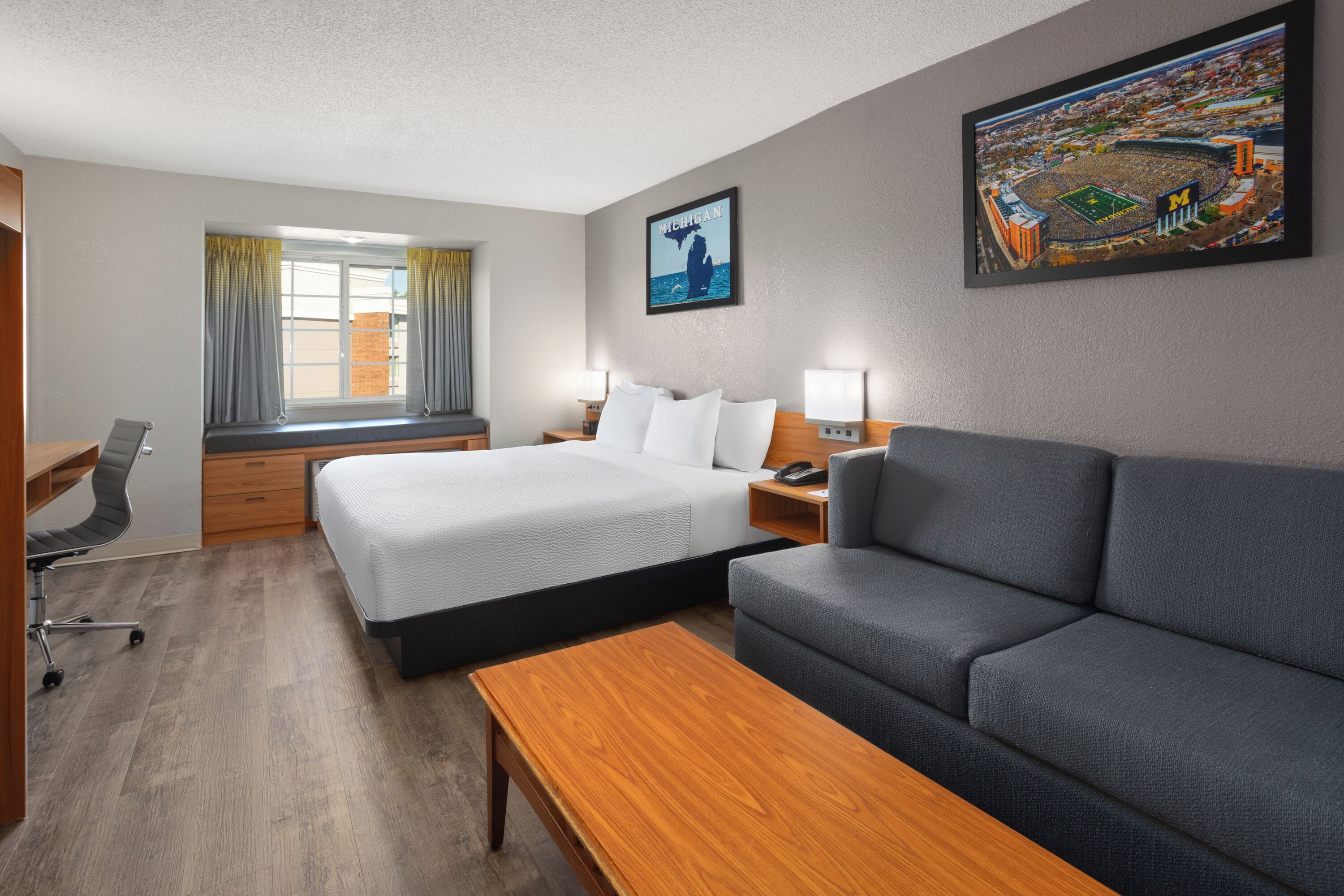 Een hotelkamer met een bed, een bank, een bureau en een raam met gordijnen.
