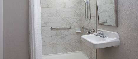 Un baño con ducha, lavabo y espejo.