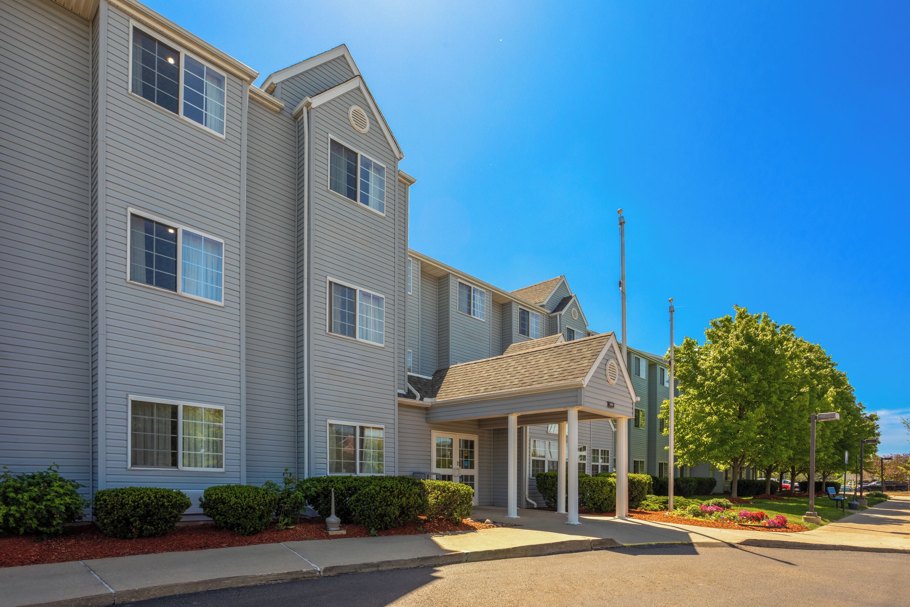 A multi-story residential building with a covered entrance and landscaped front yard.