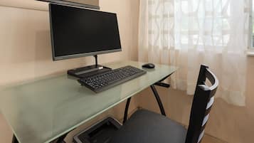 Uma configuração de escritório moderna com uma mesa de vidro, um monitor preto, um teclado e um mouse.