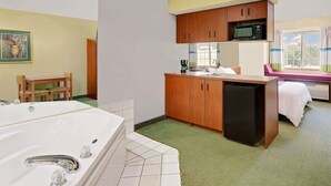 A compact hotel room with a kitchenette, a dining area, a large bathroom with a jacuzzi, and a window with a view. - Microtel Inn & Suites by Wyndham Thomasville/High Point/Lexi (Thomasville)