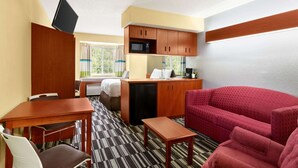 A compact hotel room with a kitchenette, a dining area, a sofa, and a bed. - Microtel Inn & Suites by Wyndham Thomasville/High Point/Lexi (Thomasville)