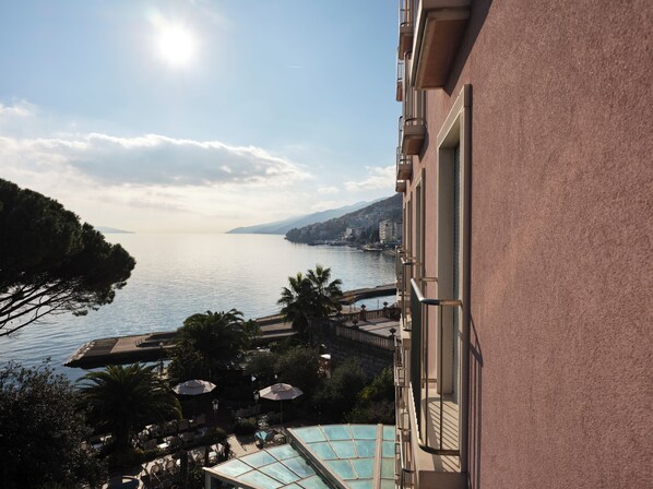 A hotel with a pool, outdoor seating, and a view of the sea and mountains.