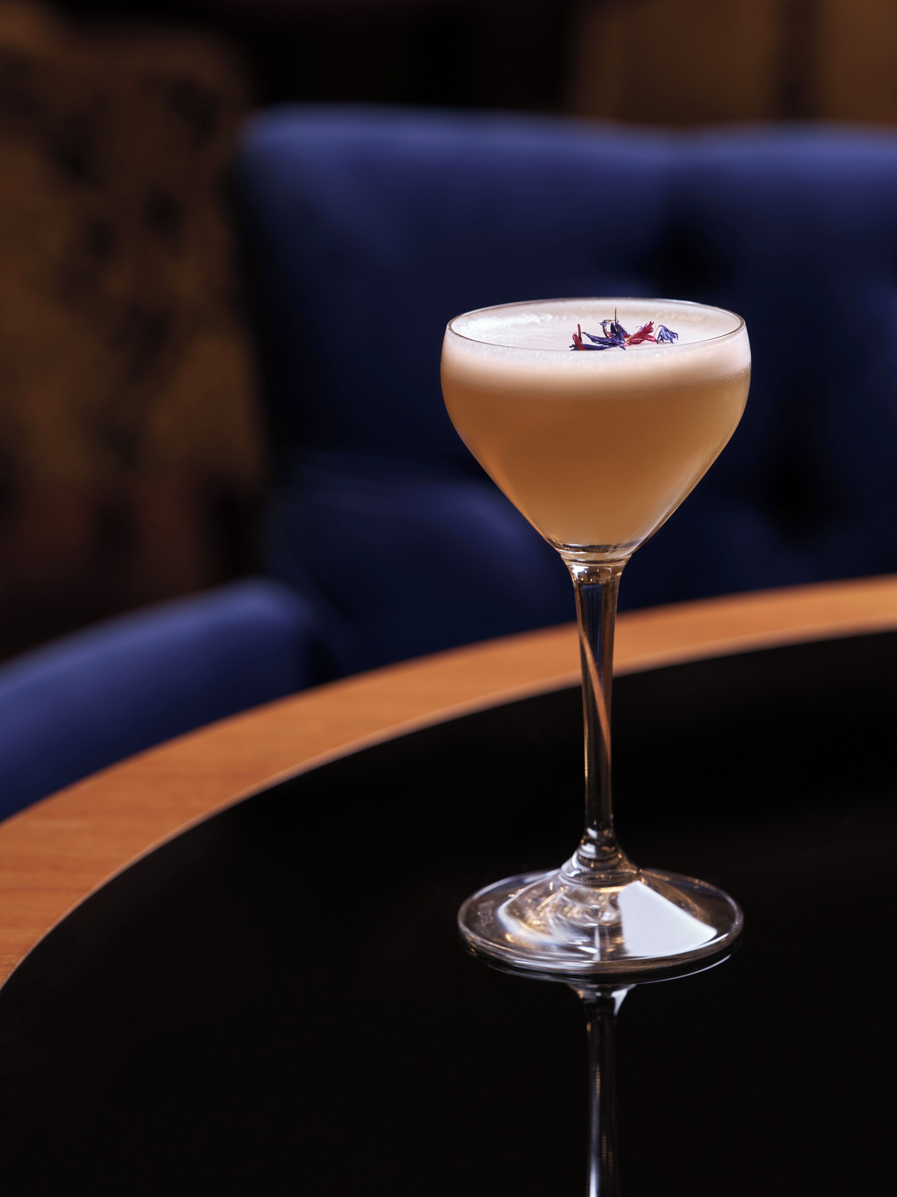 Un verre à martini contenant une boisson crémeuse, posé sur une table ronde.