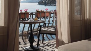 Un balcón con mesa y sillas, con vista a una masa de agua y montañas distantes.