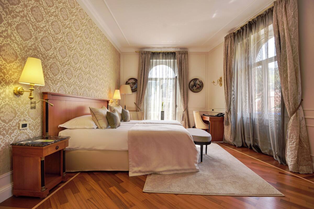 Una habitación de hotel con una cama grande, dos lámparas de noche, un escritorio y una silla.