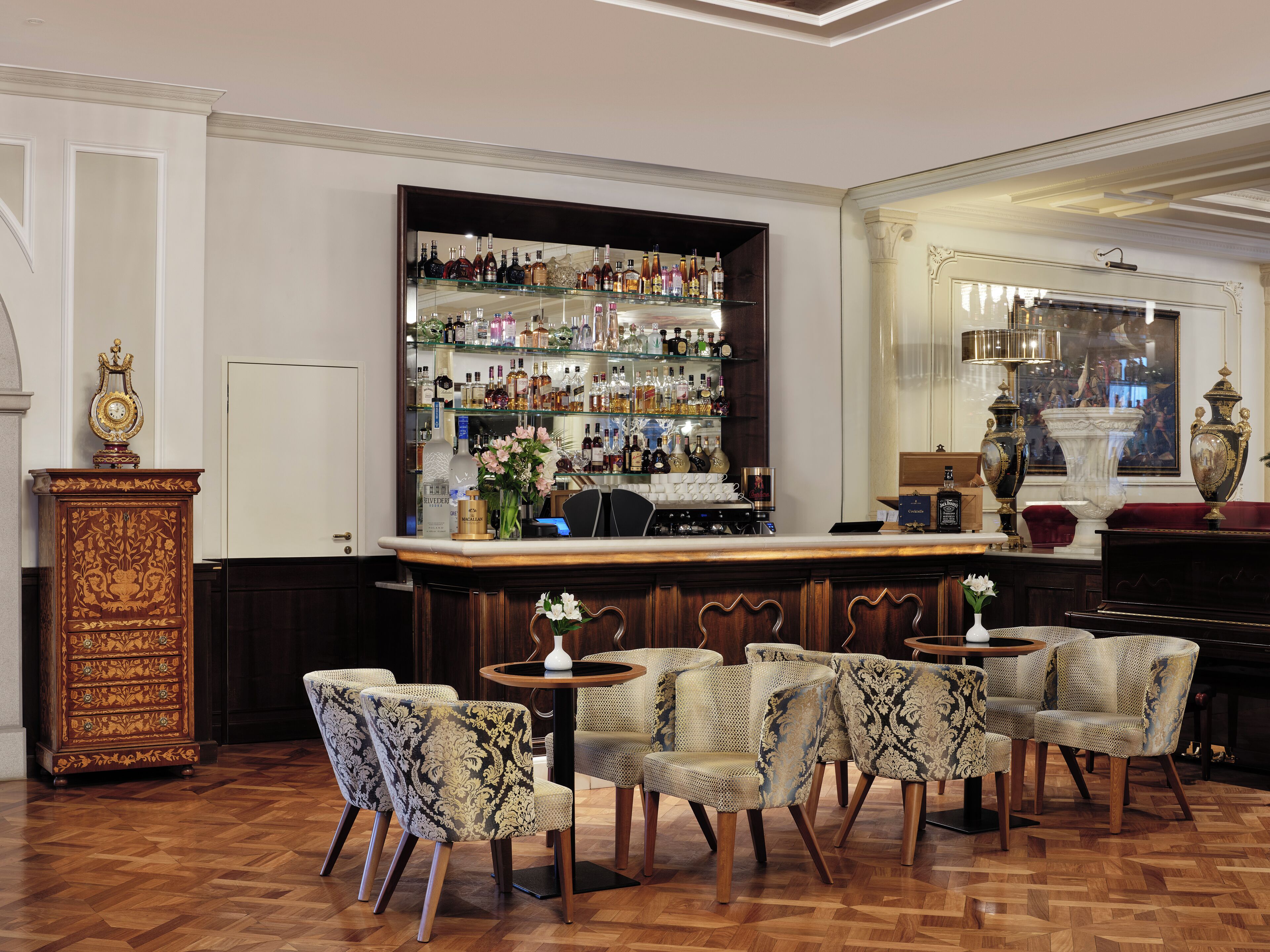 A bar area with a variety of liquor bottles, a bar counter, and seating with patterned chairs.