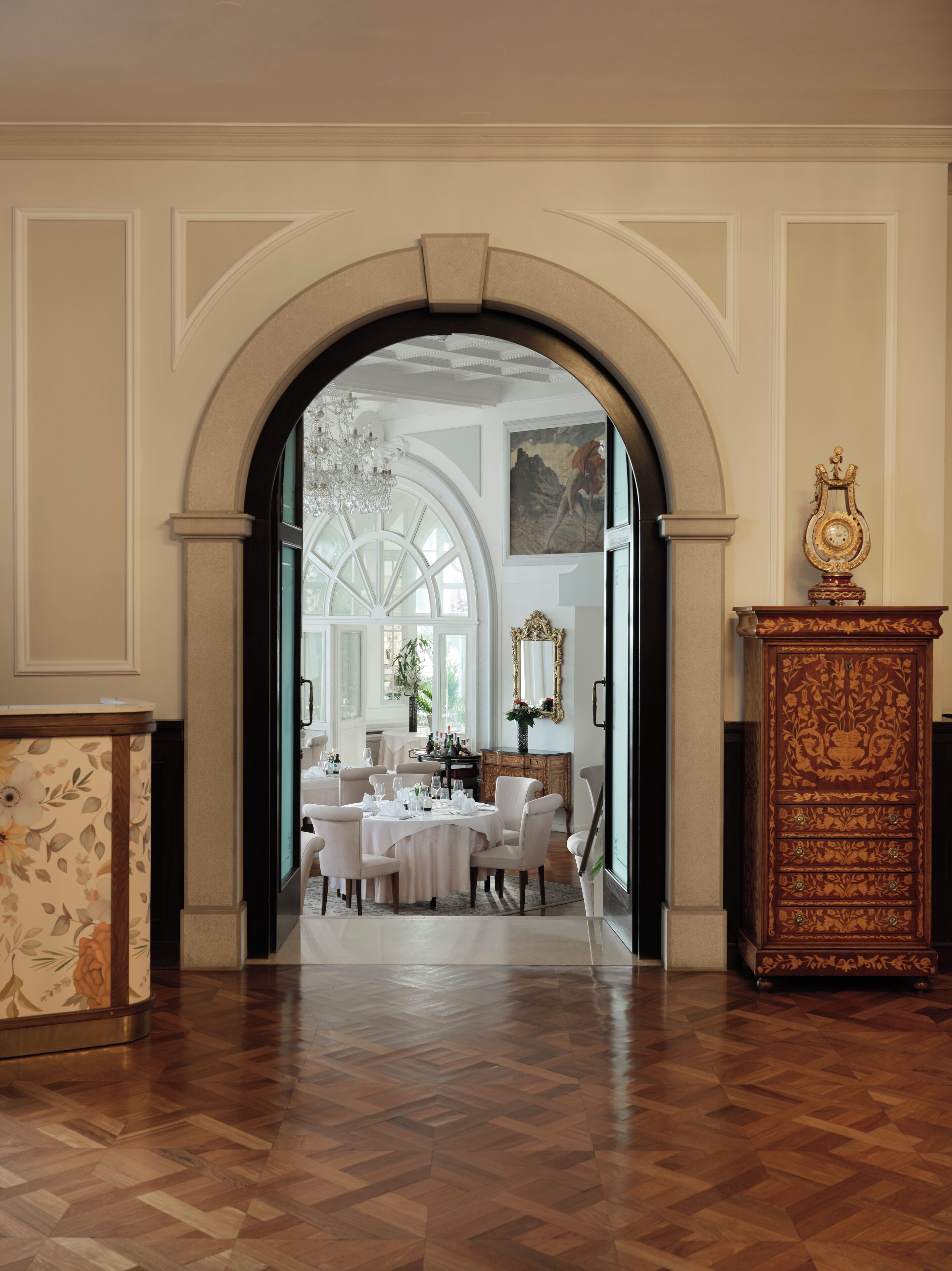 Un comedor formal con candelabro, un espejo grande y un aparador de madera.