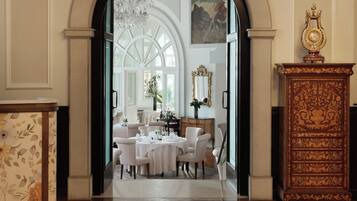 Un comedor formal con candelabro, un espejo grande y un aparador de madera.