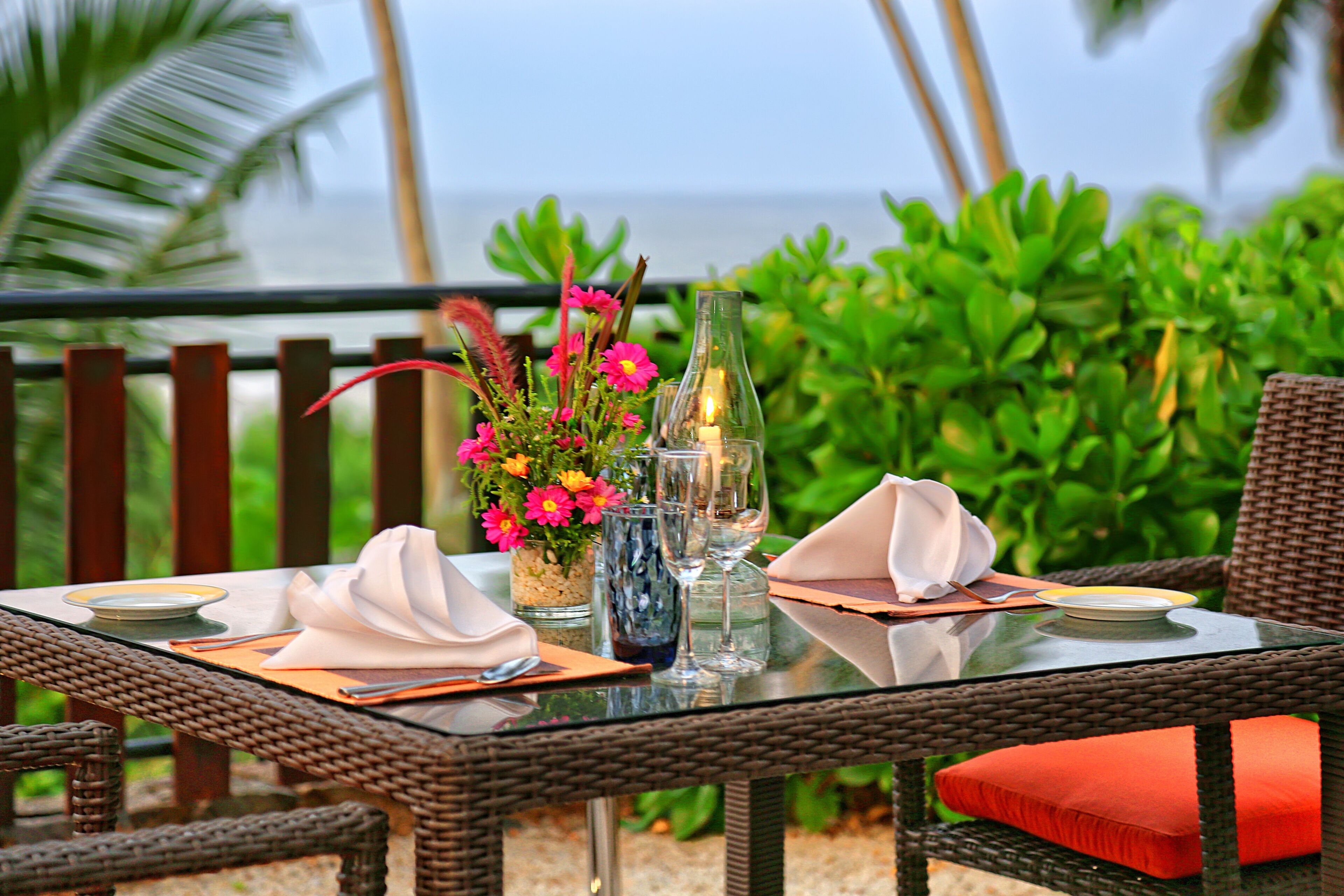 A dining table set with a vase of flowers, a candle, and a glass of water.